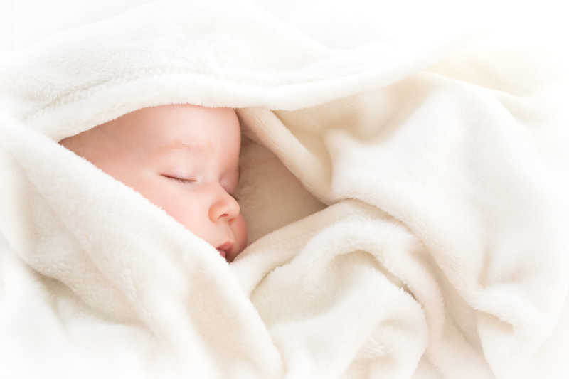 睡在柔软的白色毯子上的婴儿