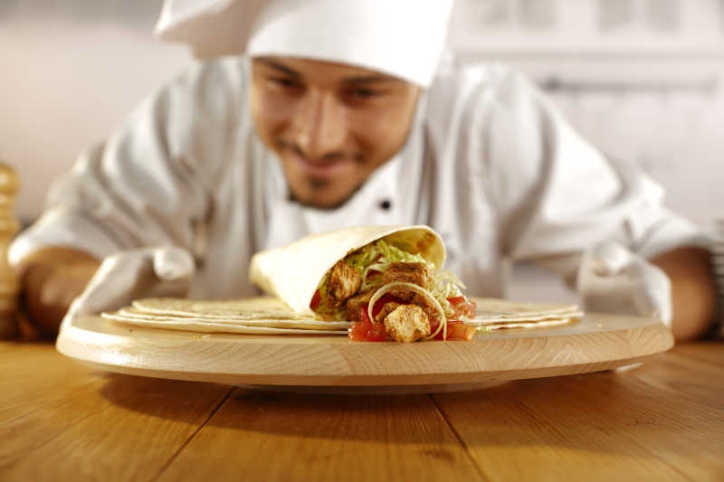 制作鸡肉卷的厨师微笑着