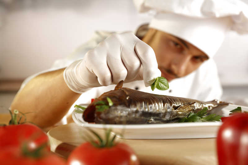 厨房内专心点缀鱼的厨师