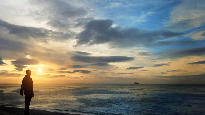 日出时站在海边的男人