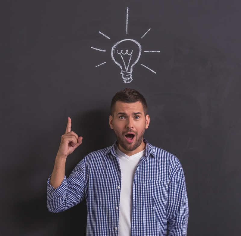 英俊的年轻人指着头顶黑板上的电灯