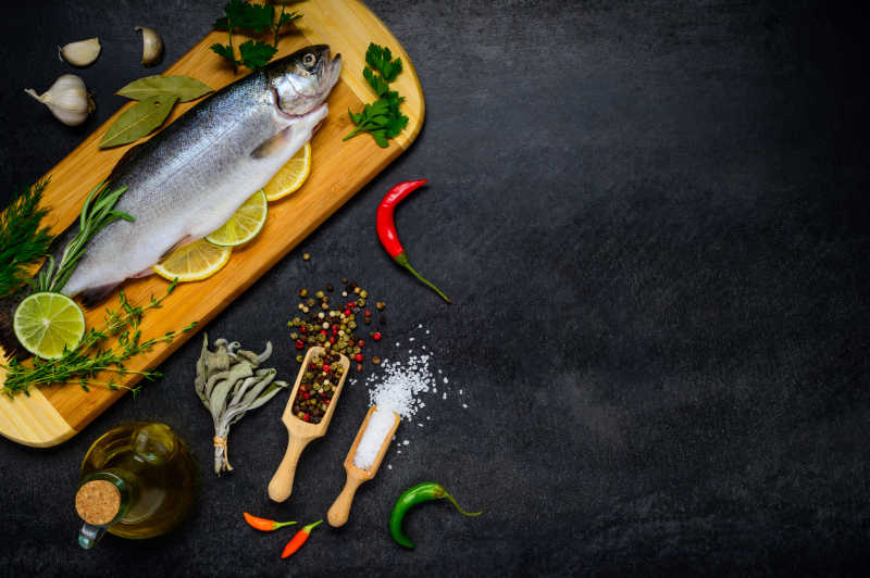 案板上新鲜的鱼和旁边的烹饪原料