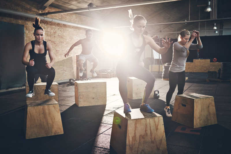 在健身房里做跳箱健身的年轻男女