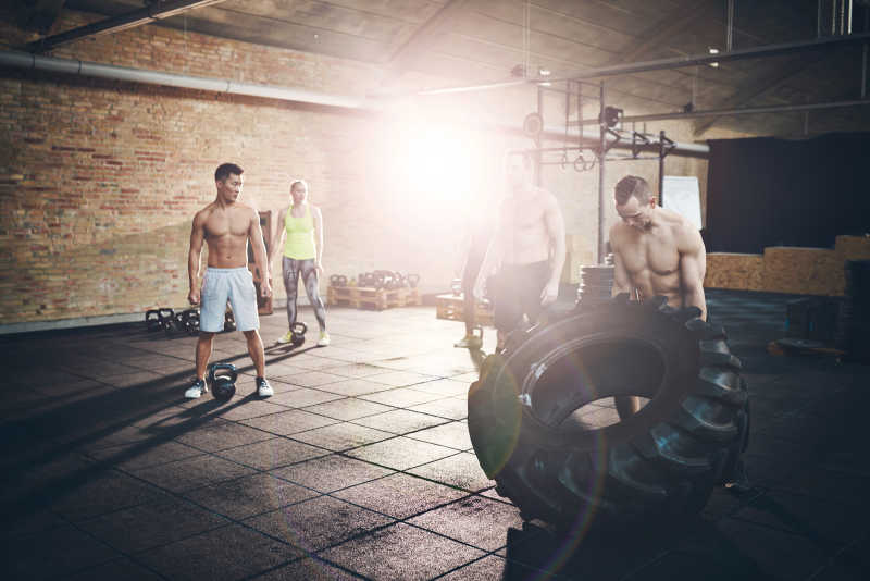 在健身房金丝进行移动大轮胎力量运动的健身运动员