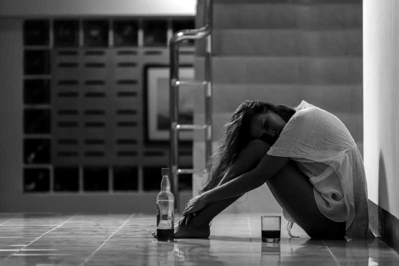 黑色背景下在楼道中饮酒的年轻女子