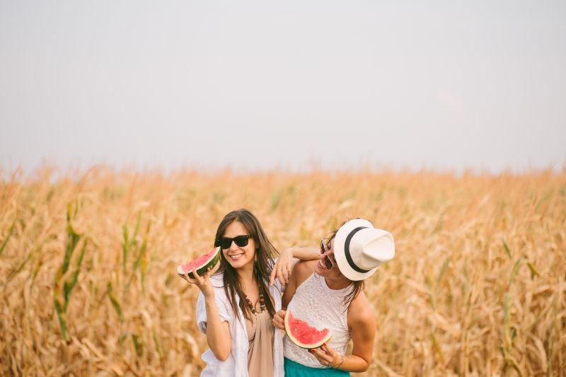 在乡下田边拿西瓜吃的两个美女