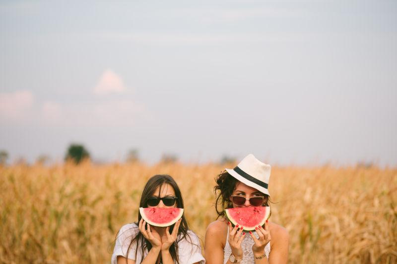 在田边拿着西瓜的两个美女