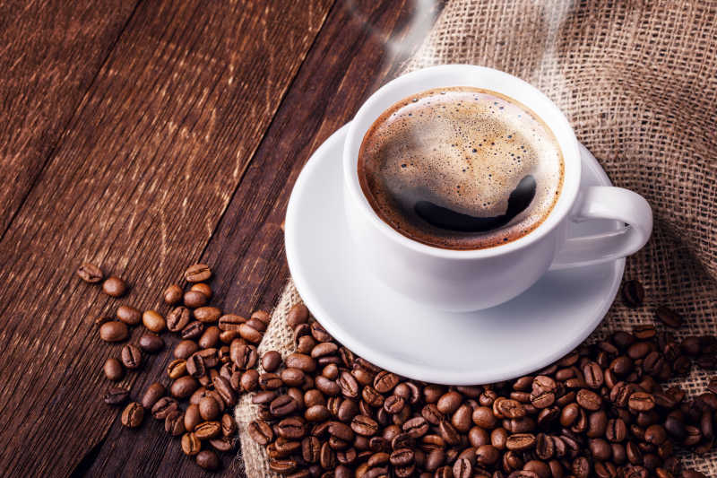 木桌上的一杯热咖啡和咖啡豆
