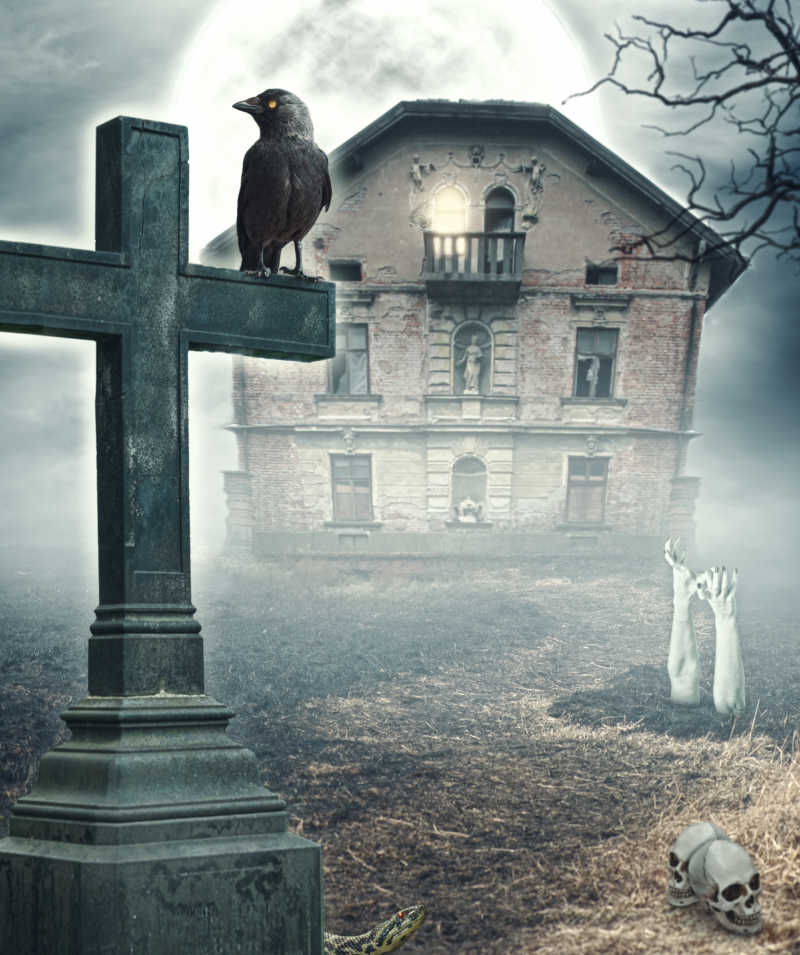 墓地的小屋前黑色的十字架上站着一只黑色的乌鸦
