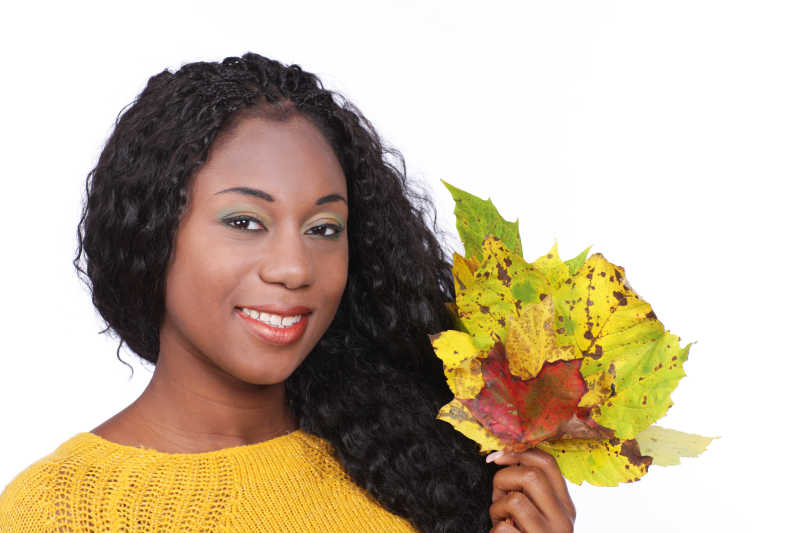 白色背景下拿着落叶的非洲女孩
