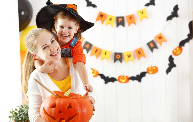 漂亮的妈妈与可爱的孩子为万圣节装修房子