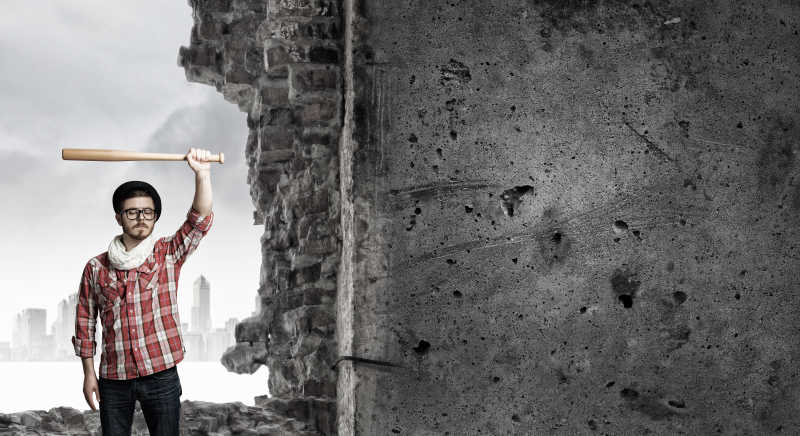 破败建筑前举着棒子的男人