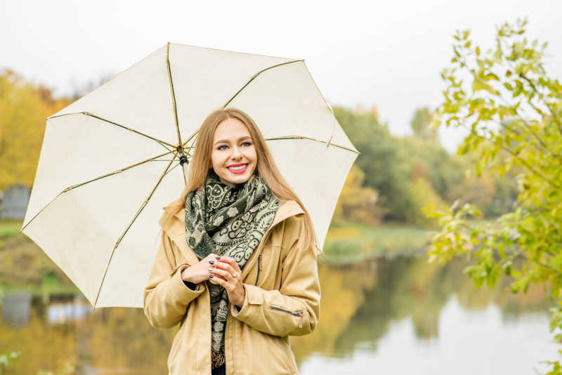 优雅女人带着伞在秋天的公园里