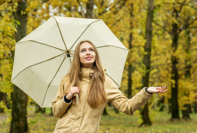 美丽的优雅女人带着伞在秋天的公园里