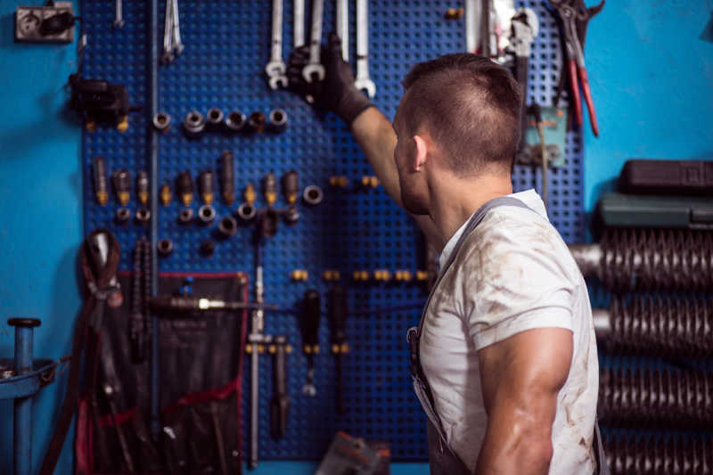 蓝色背景下正在拿扳手的修理工