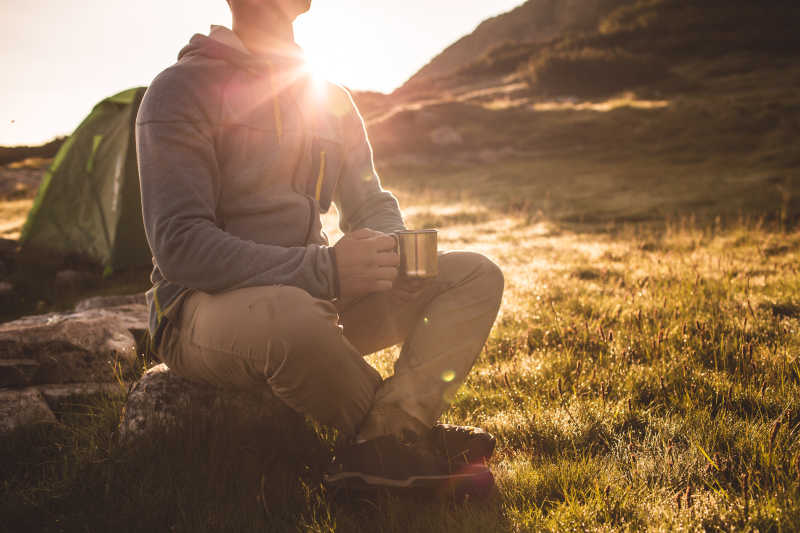 夕阳下坐在草地上喝水的男人