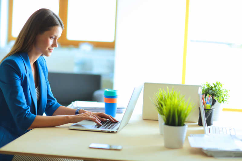 坐在桌上的女人正在用笔记本工作写数据