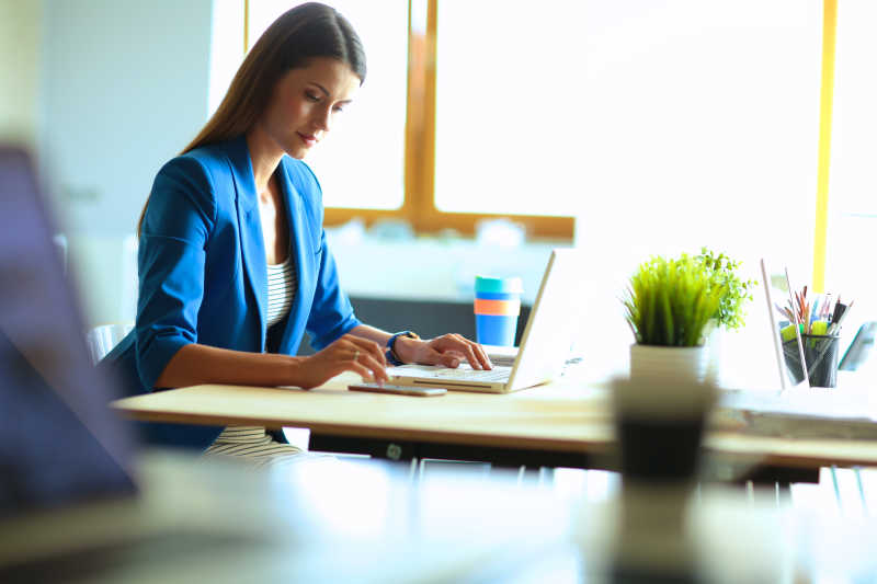 坐在桌上的女人正在用笔记本工作