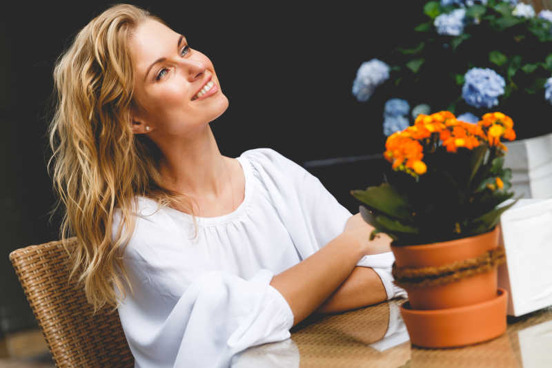 坐在咖啡馆桌子上微笑的金发女孩