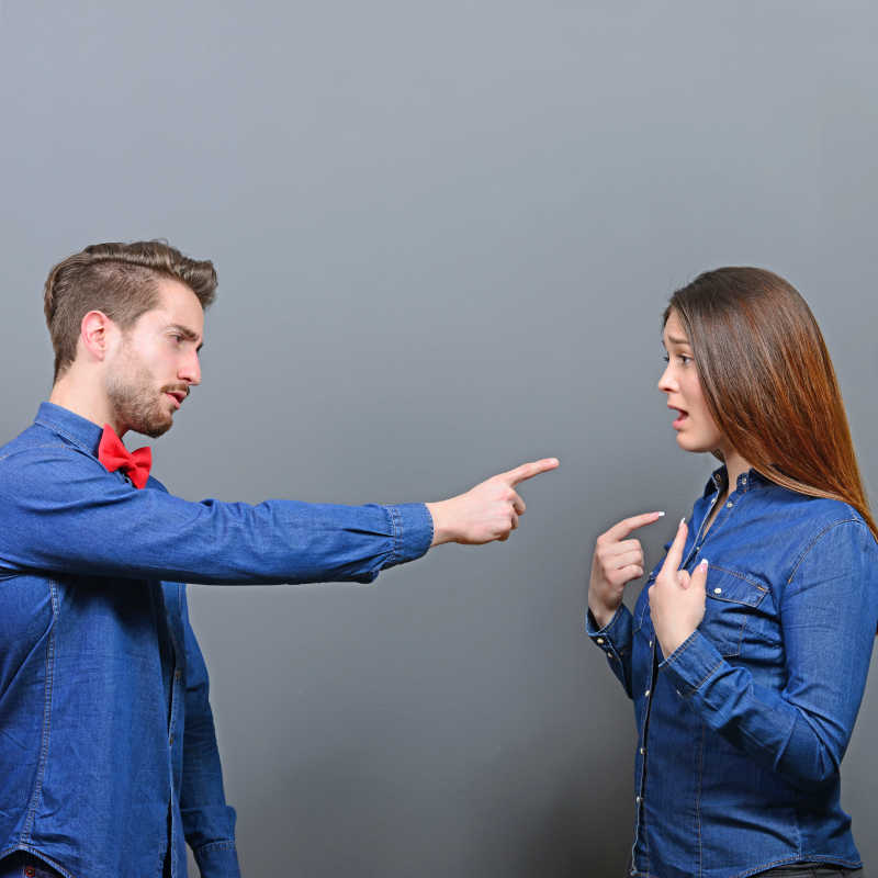 灰色背景上男人正在指责他的妻子