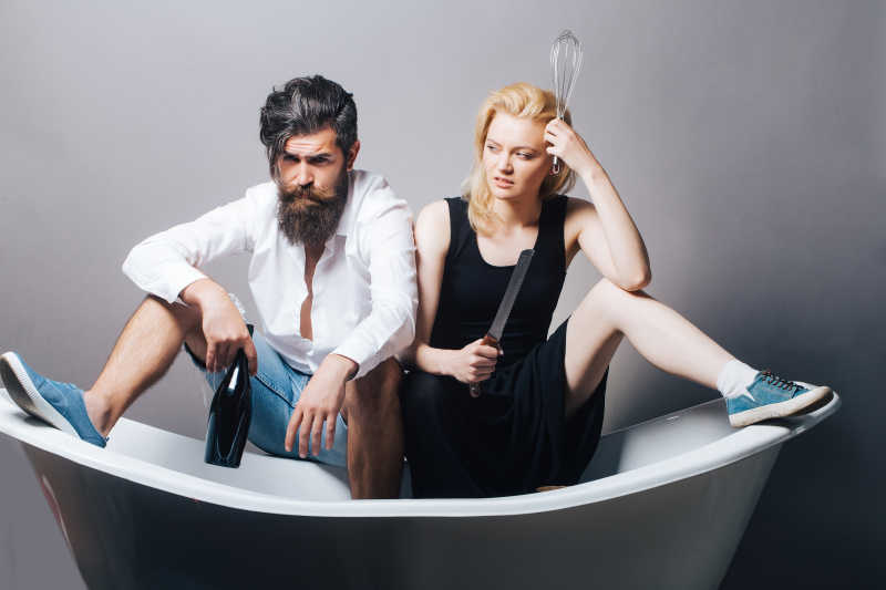 坐在浴缸上拿着酒瓶的男人和拿着刀的女人