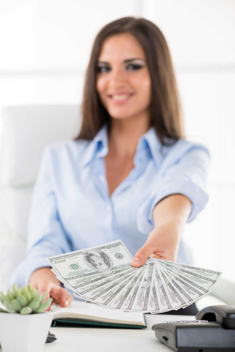 坐在办公桌上的年轻女商人拿着美女