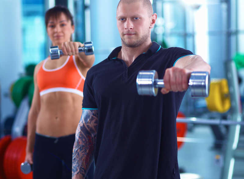 健身房里的健身的美女与她的教练