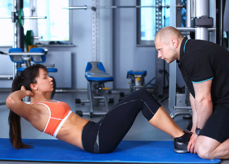 与教练在健身房锻炼的健美女子