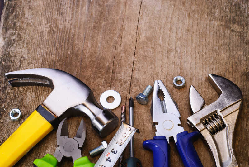 老旧的木板上摆放着各种家庭修理工具
