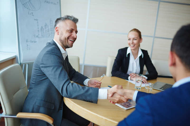 坐在会议桌上握手的男士