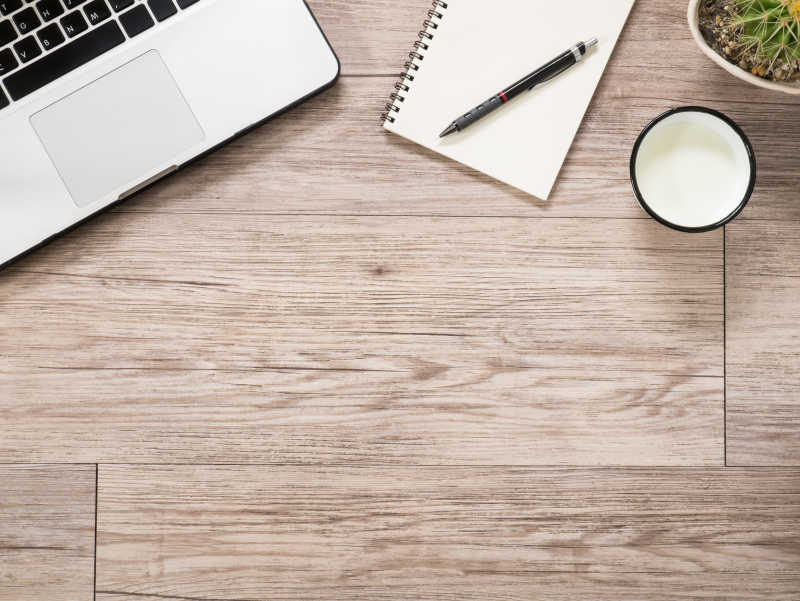 笔记本电脑和牛奶杯在木制背景下