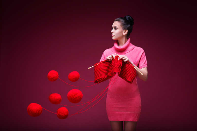 性感的外国美女在用红色毛线织毛衣