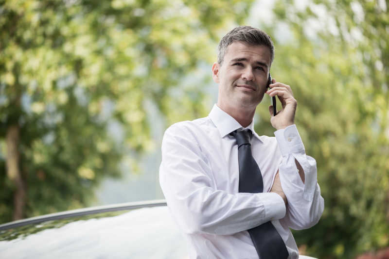 自信微笑的经理用他的智能手机打电话