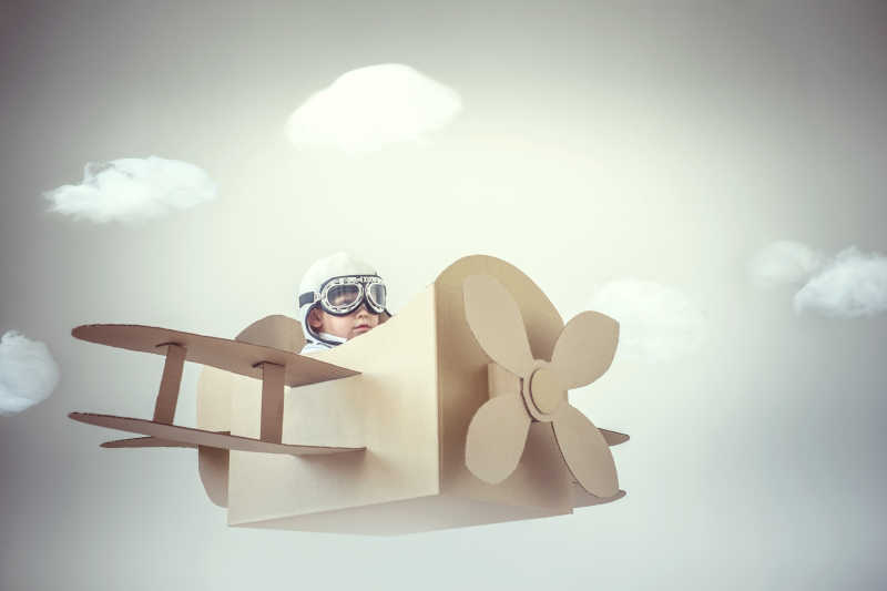 坐在纸飞机里的飞行员小男孩
