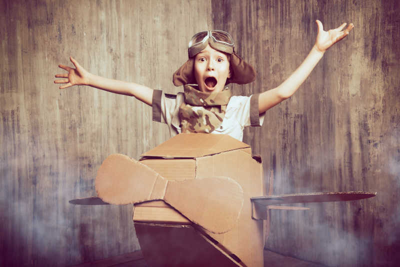 用纸箱子模拟飞机飞行的男孩子