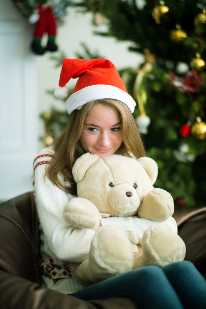 超级可爱的圣诞女孩抱着熊坐在榻榻米上休息