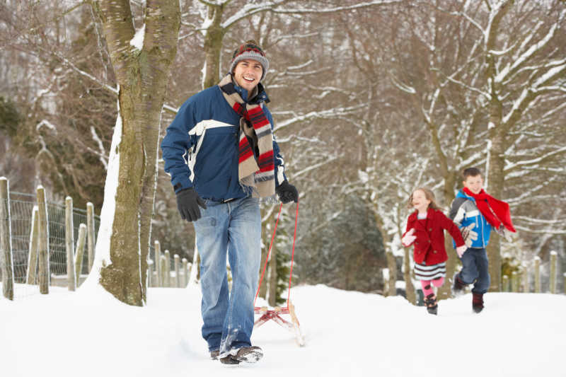 父亲在雪地上拉雪橇上与孩子一起玩耍