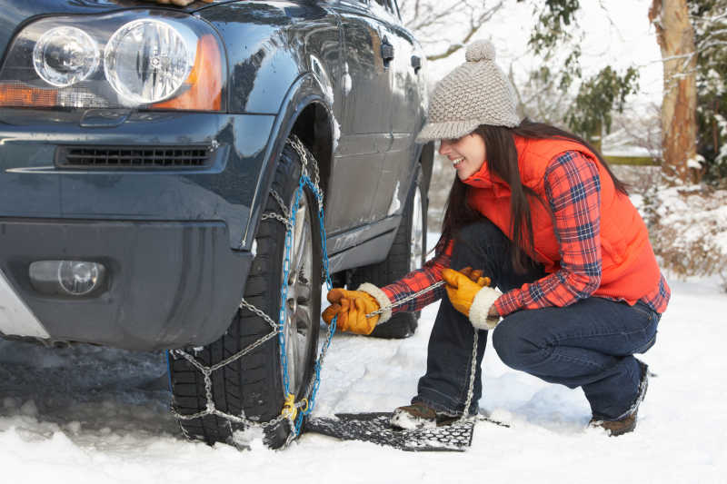 女人把雪链放在汽车轮胎上