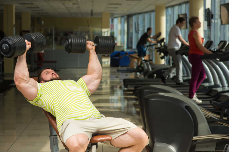 男人用哑铃在健身房锻炼