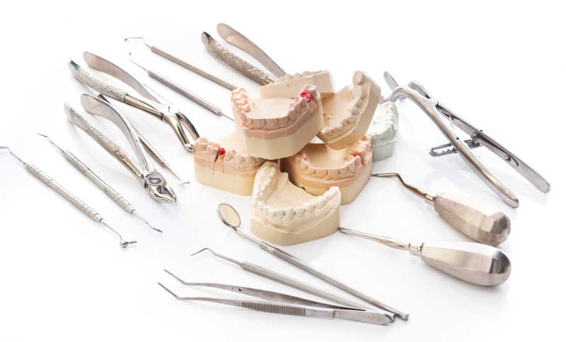 白色桌子上的牙科工具与假牙模型