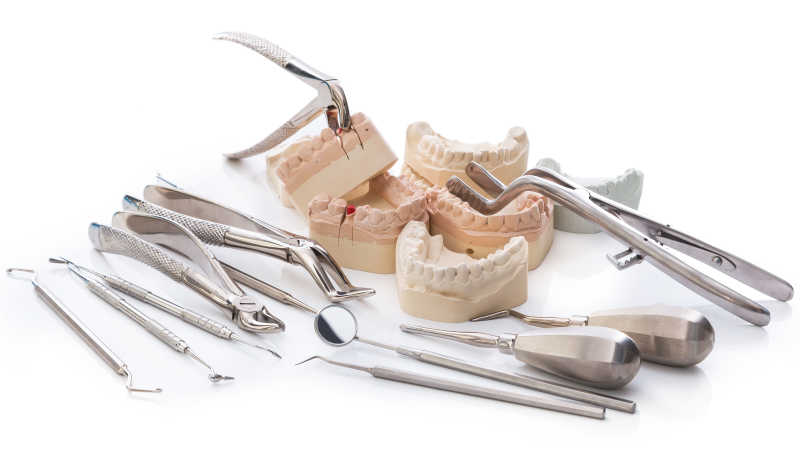 白色背景下的牙科工具与牙齿假牙模型