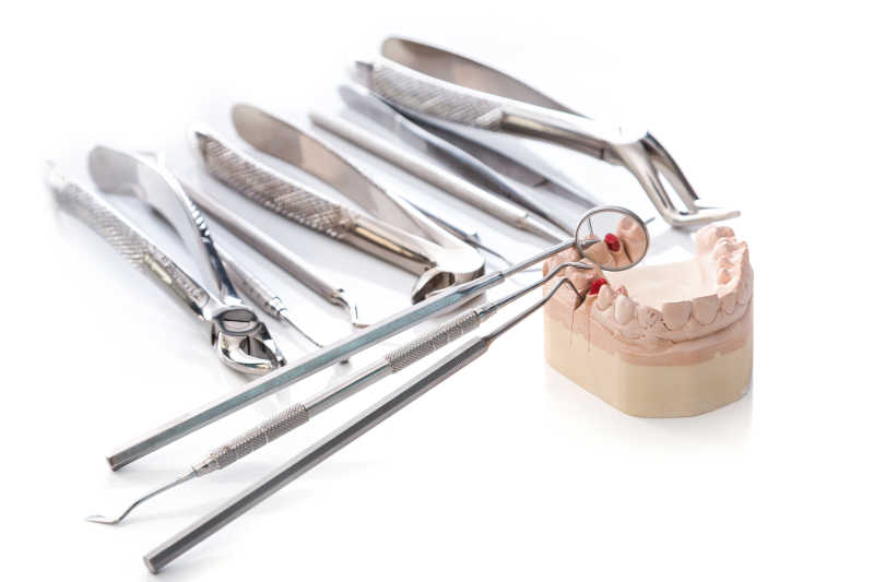 白色背景下的牙科工具与假牙模型