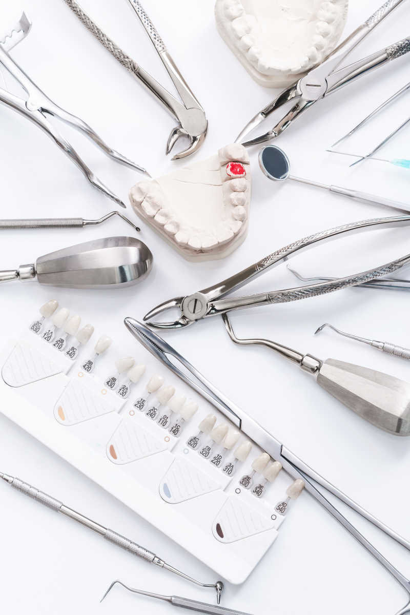 白色桌面上的牙科工具与牙齿假牙模型