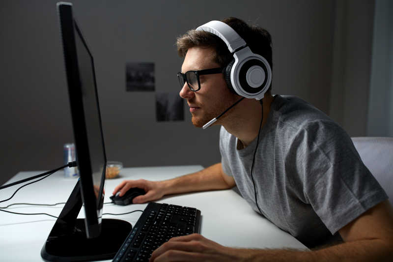 戴耳机的年轻男人在家玩电脑游戏