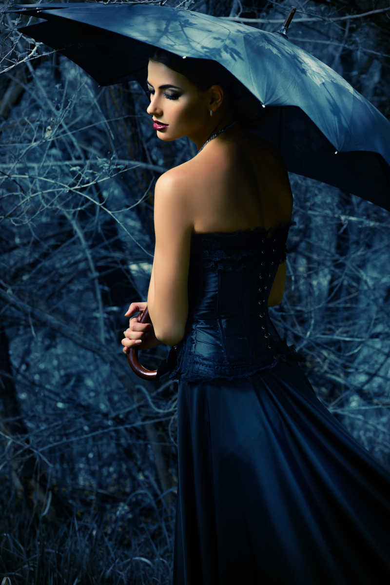 一位身穿黑色长裙礼服打着黑伞的女人