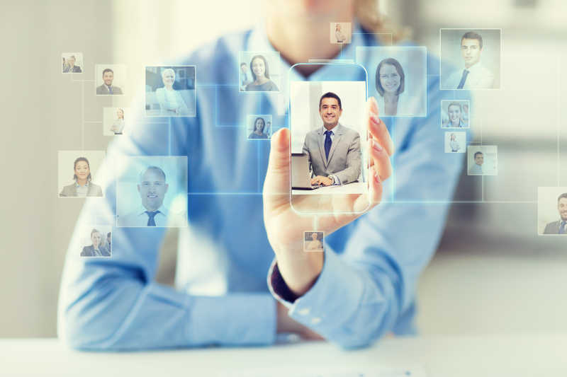 女子手持屏幕上显示带有联系图标的透明智能手机