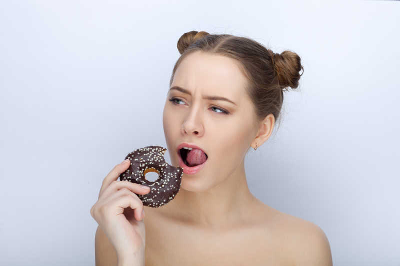 白色背景下对甜甜圈感兴趣的女孩