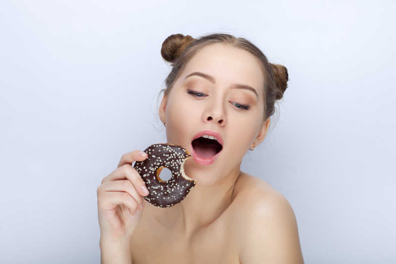 白色背景下拿着甜甜圈的可爱女孩