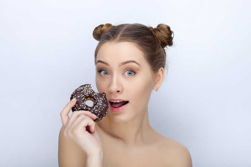 白色背景下用手拿着甜甜圈的女孩