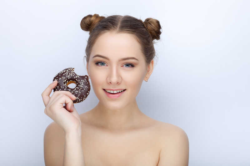 白色背景下的拿着甜甜圈的漂亮女孩